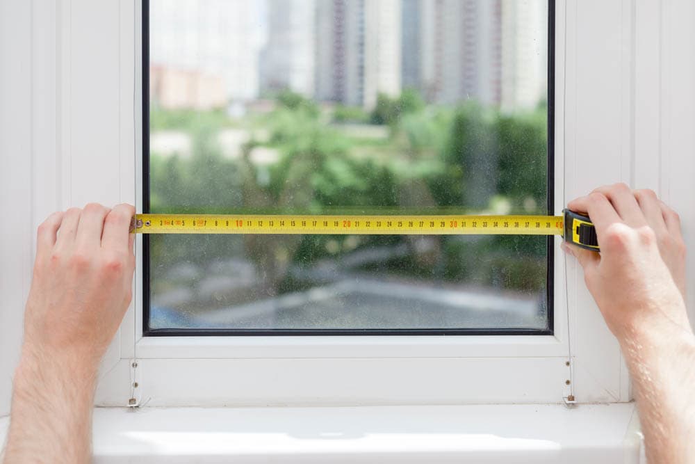 Handyman measuring width of a window.