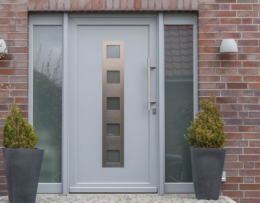 Modern house front with shrubbery and light grey composite door.